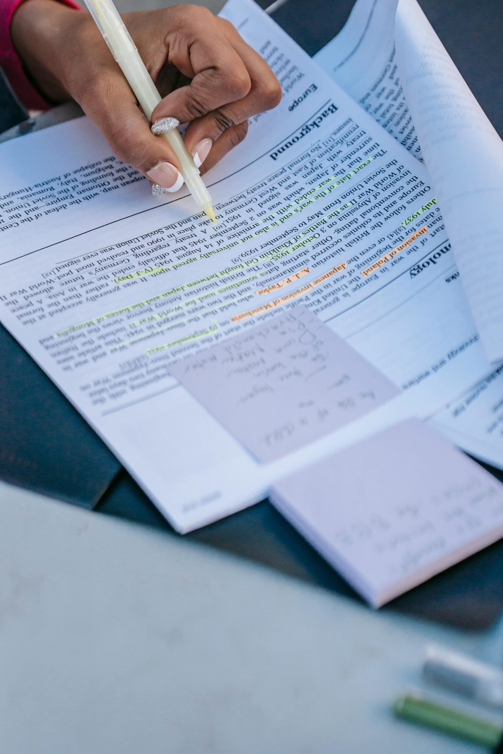 Close-up of a person studying with documents and notes, highlighting keywords and text.