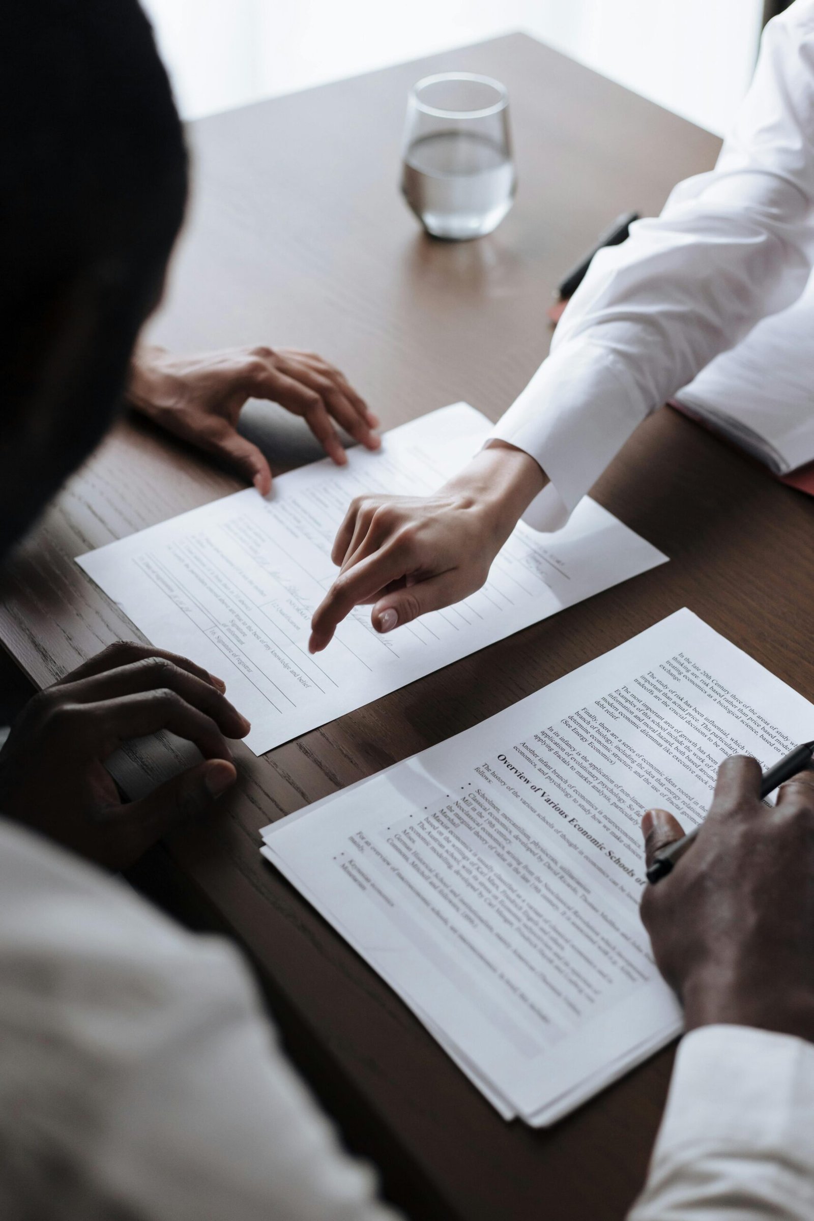 A professional business meeting with document signing, showing hands in action indoors.